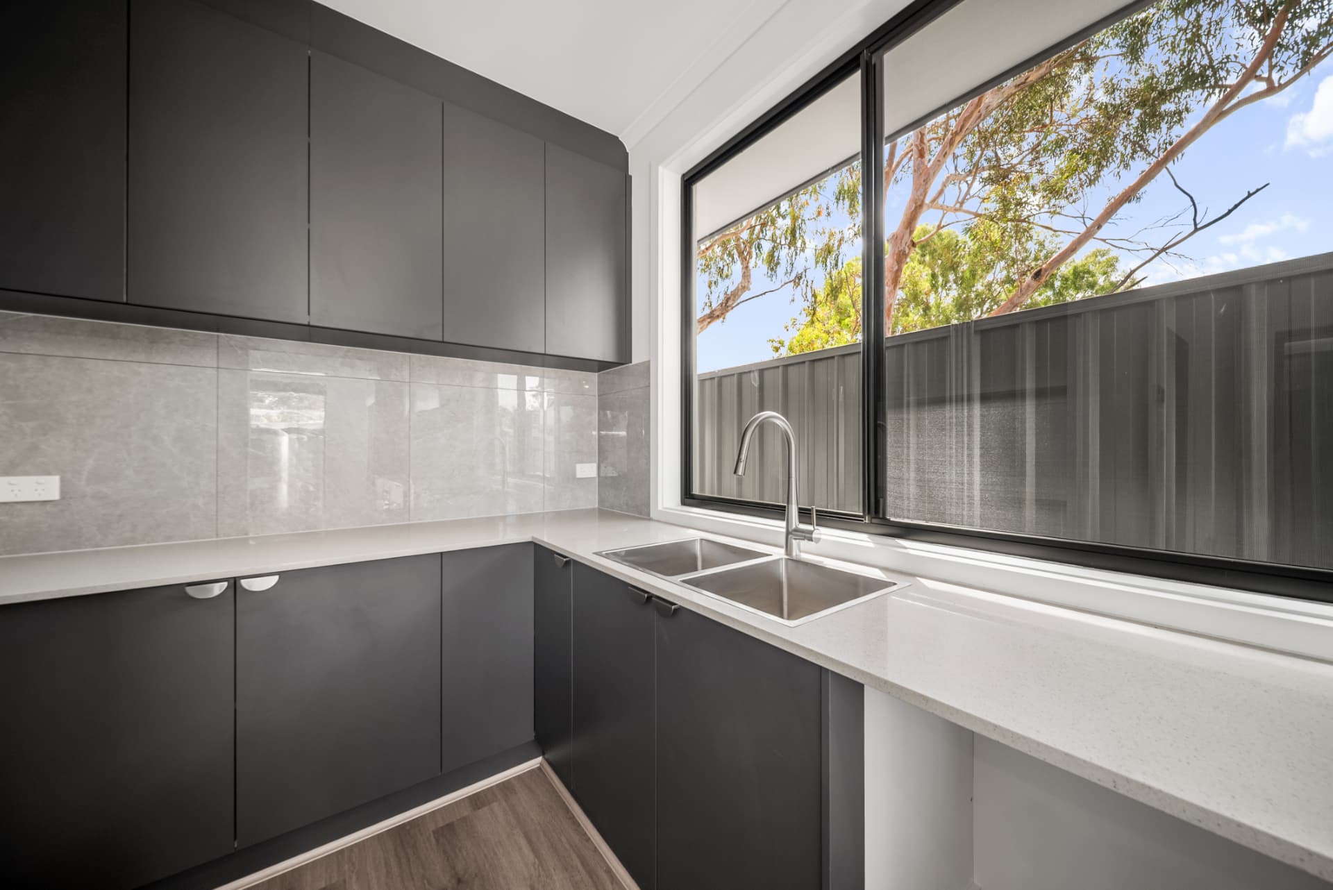 Kitchen pantry with charcoal cabinetry, stone benchtop and garden outlook