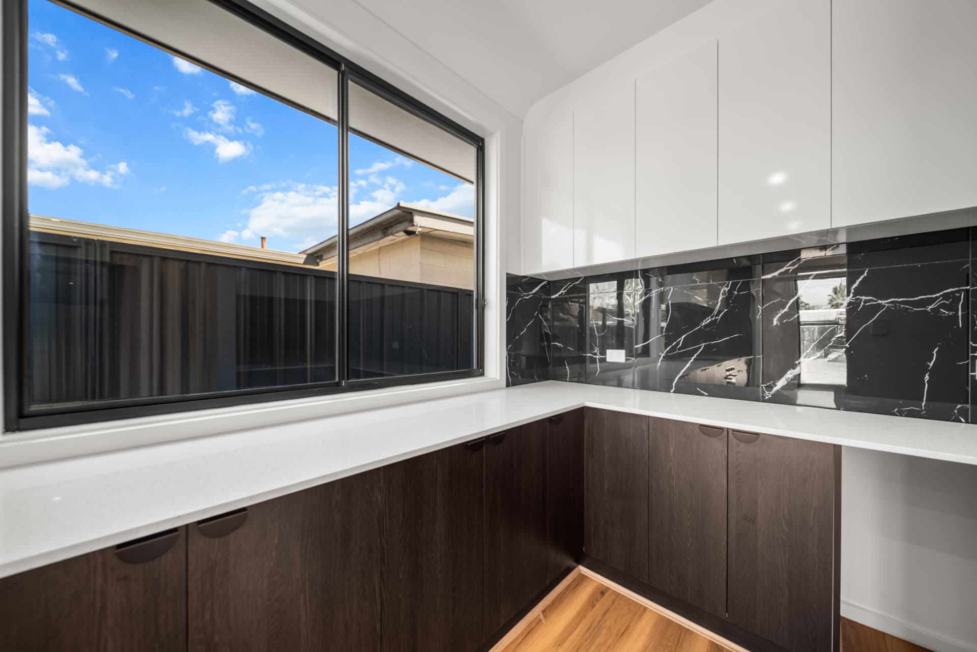 Butler's pantry with dark timber cabinetry and marble-look splashback